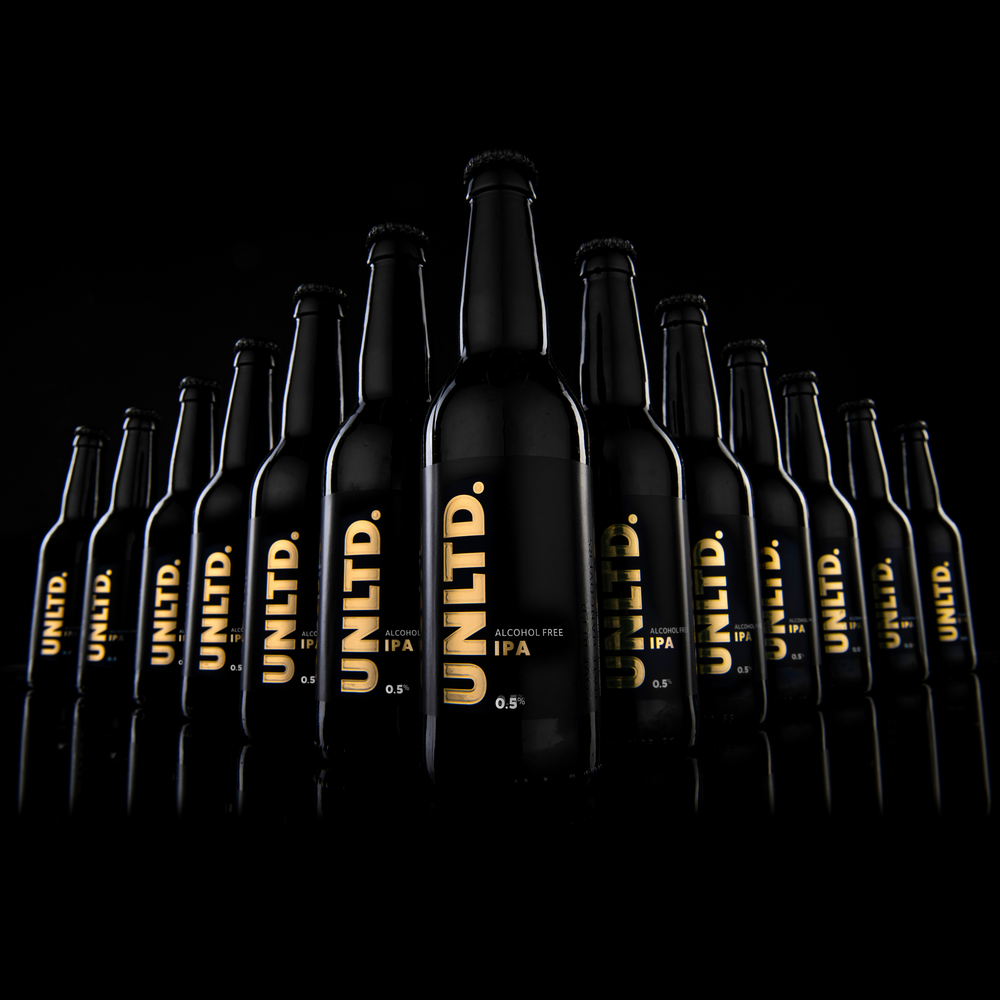
                  
                    Row of black UNLTD IPA beer bottles on a black background
                  
                