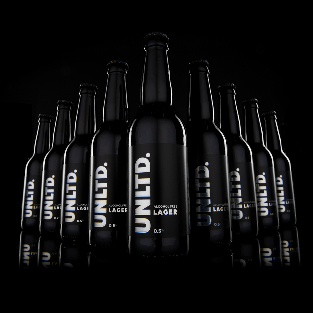 Bottles of UNLTD. Alcohol Free Lager on a black background