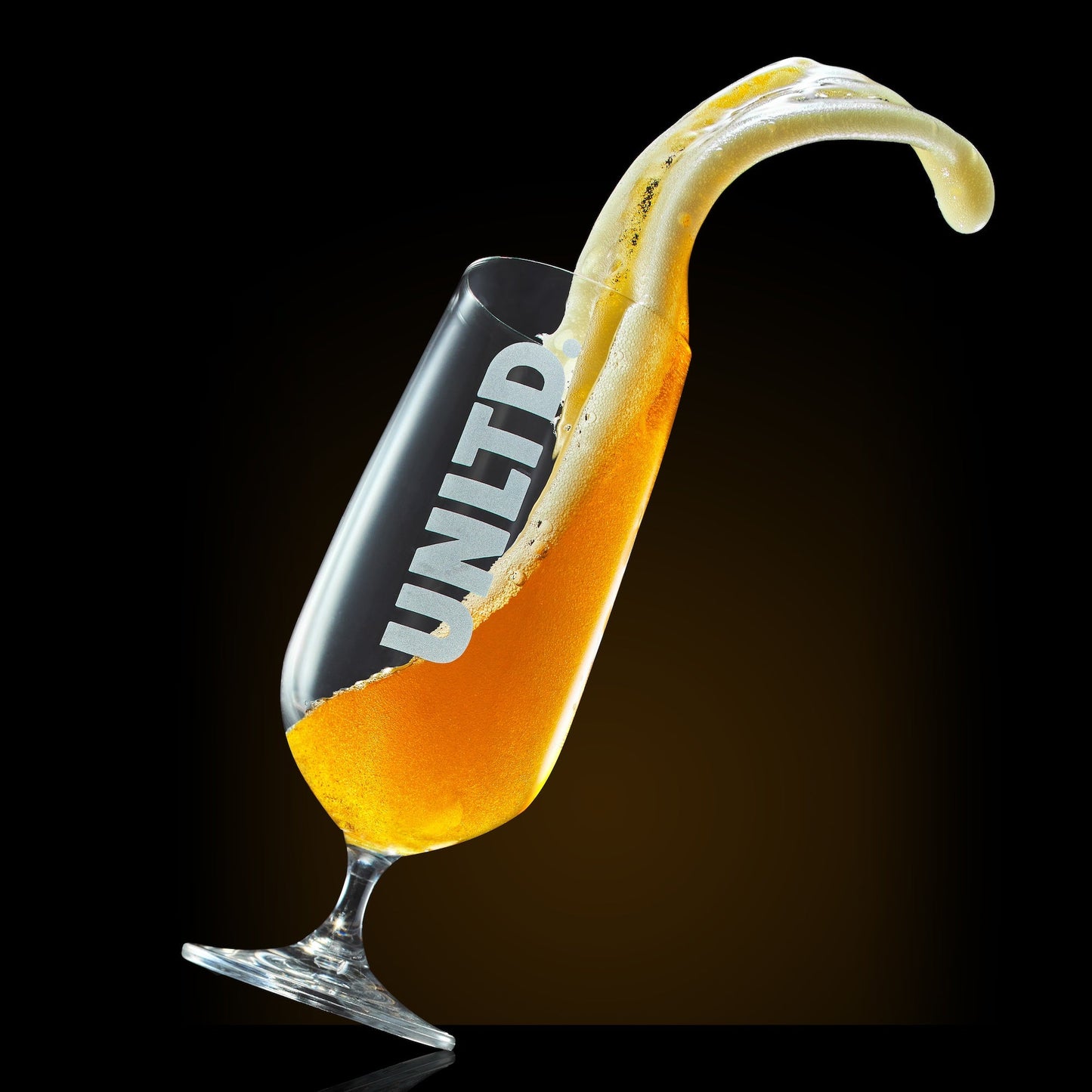 Glass of beer with a banana slice on a black background, featuring the brand 'UNLTD'.